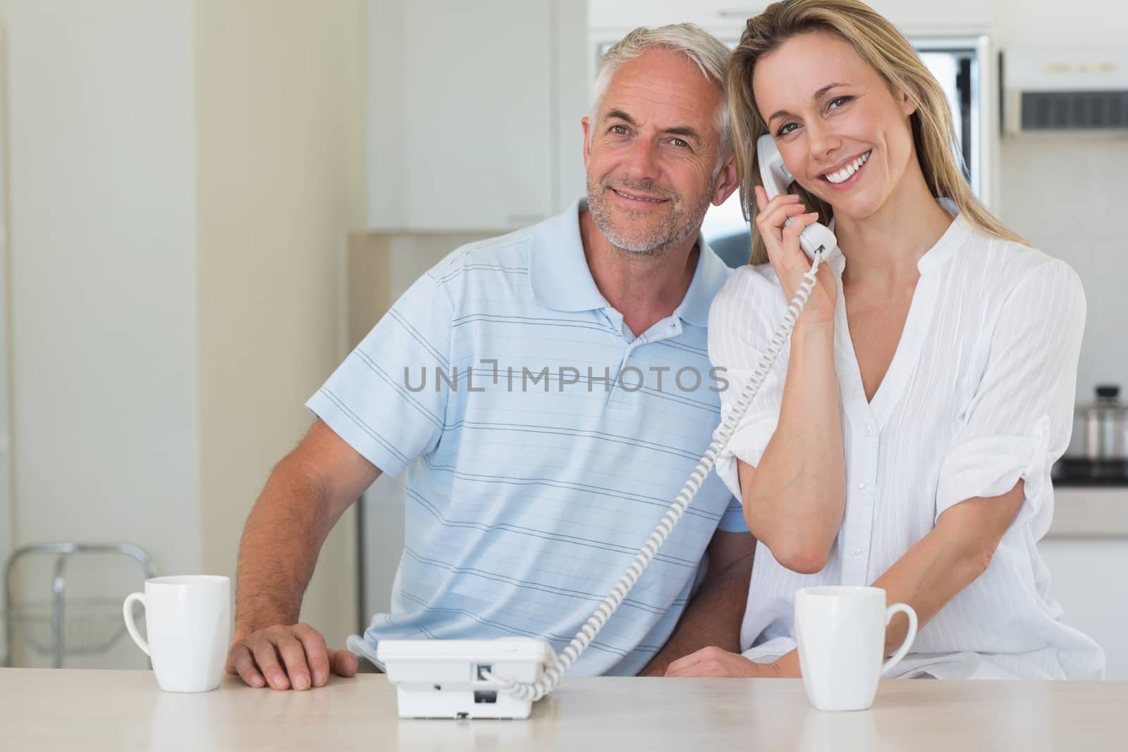 Smiling man listening in on his blonde partners phone call by Wavebreakmedia