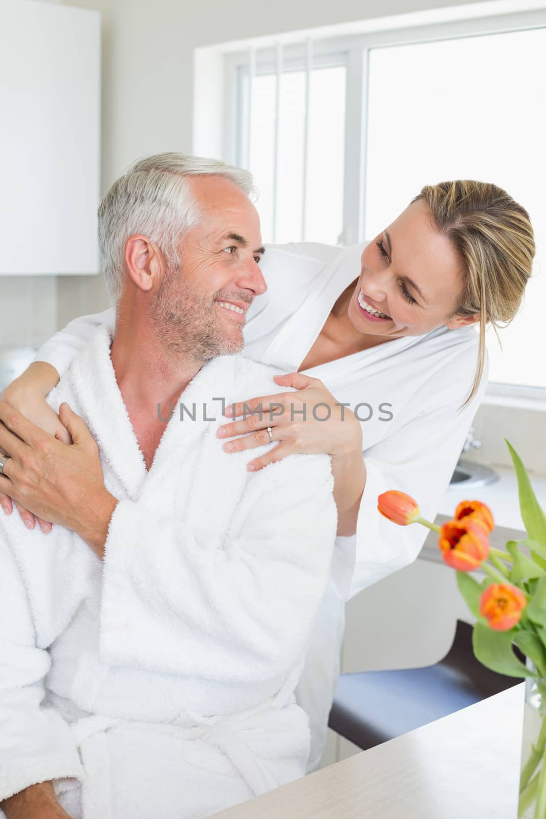 Happy couple embracing in the morning at home in the kitchen