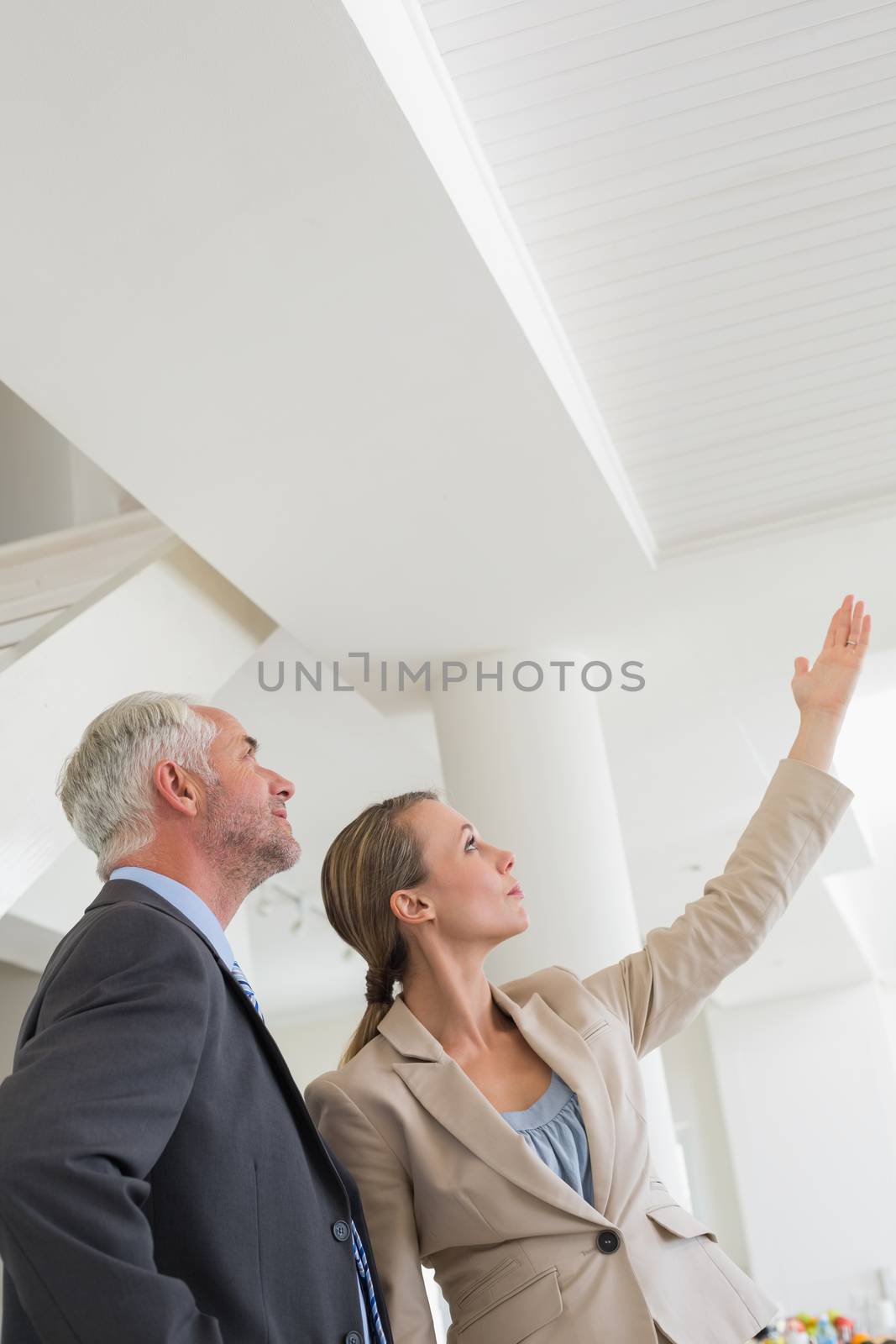 Smiling estate agent showing ceiling to potential buyer in empty house