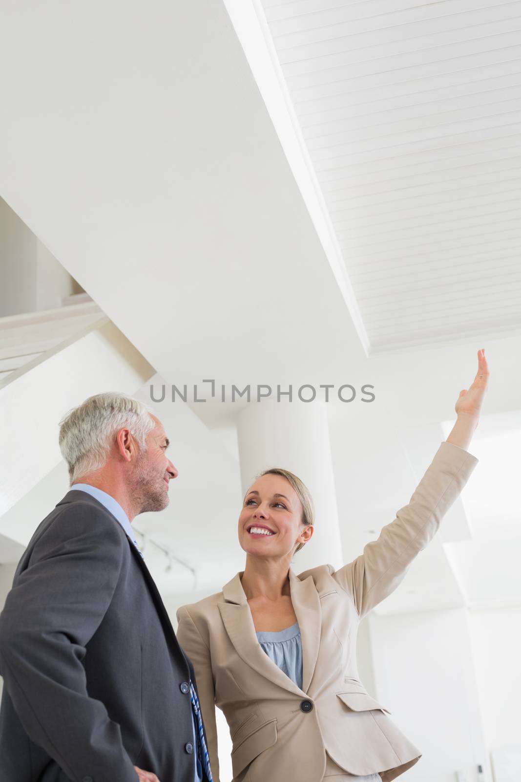Smiling estate agent showing ceiling to potential buyer by Wavebreakmedia