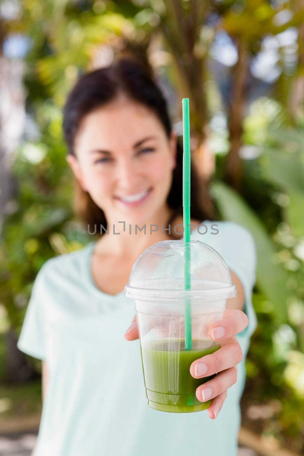 Portrait of cheerful woman showing juice while standing outdoors