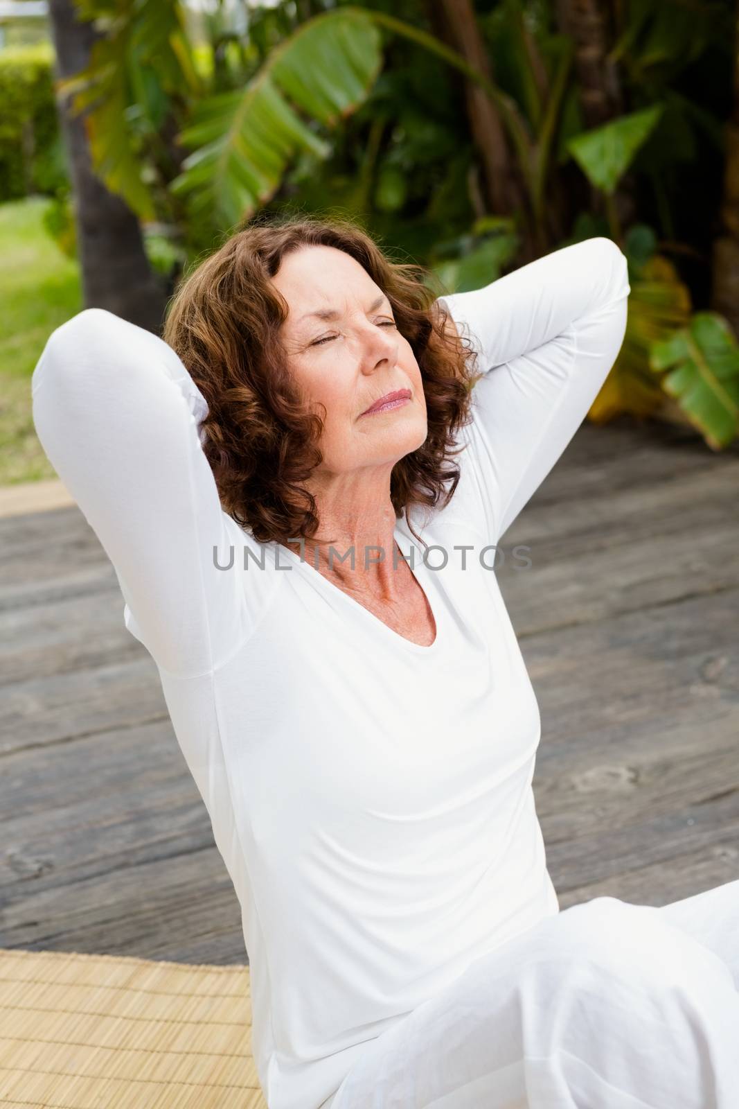 Woman with hands behind head while doing yoga by Wavebreakmedia