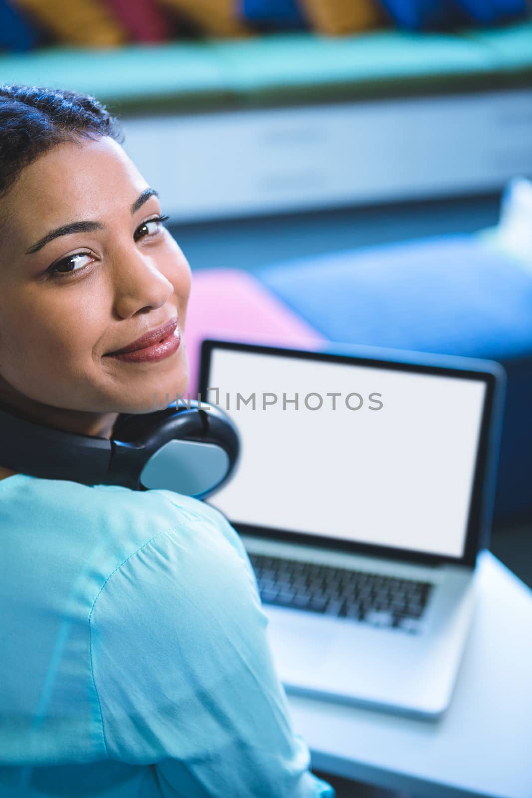High angle portrait of smiling woman using laptop in library