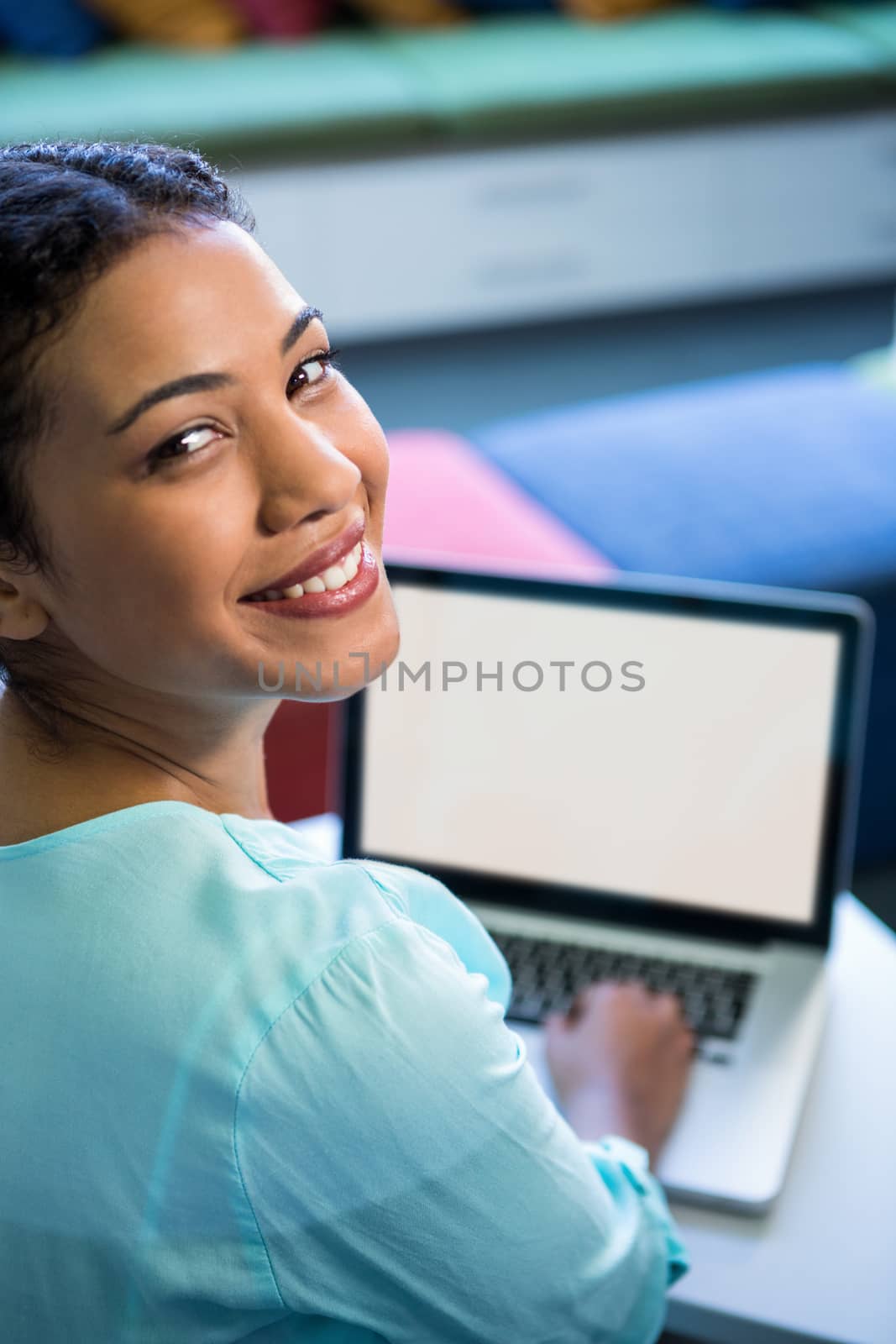 portrait of woman using laptop in library by Wavebreakmedia
