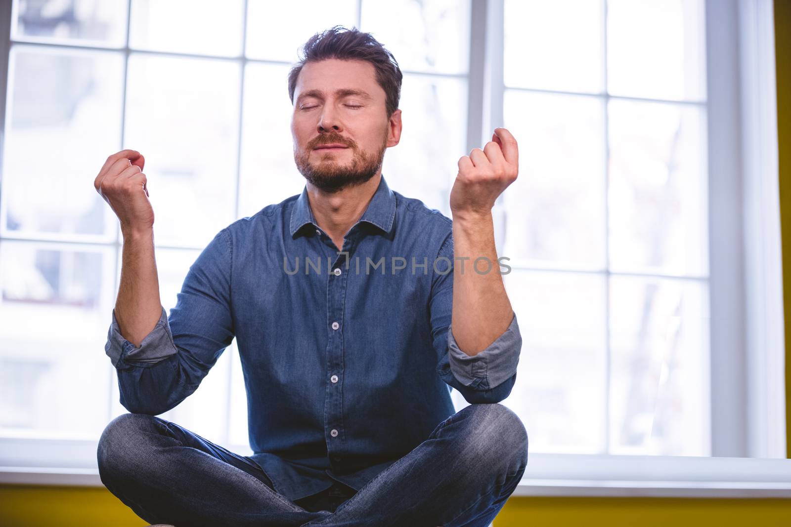 Young male executive doing yoga at creative office