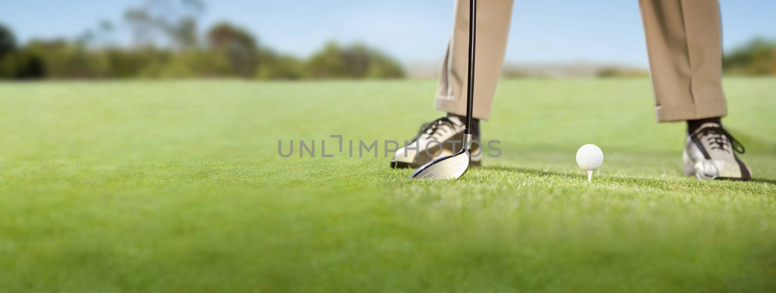 Golfer placing golf ball on tee on a sunny day at the golf course