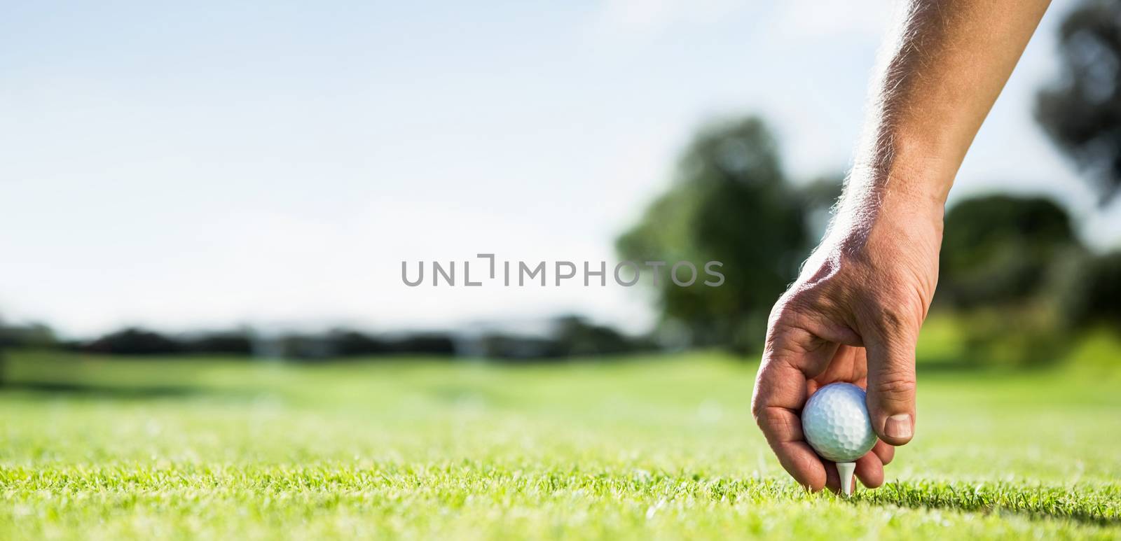 Golfer placing golf ball on tee on a sunny day at the golf course