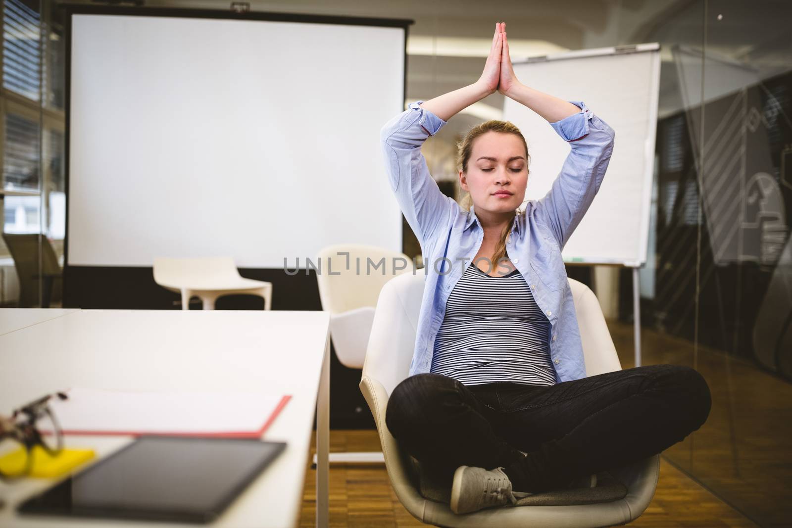 Businesswoman performing yoga in meeting room by Wavebreakmedia