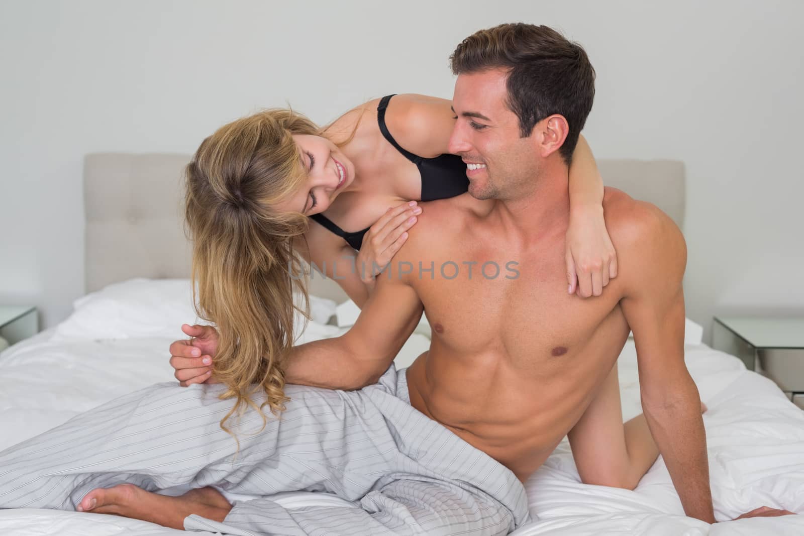 Cheerful romantic young couple in underwear in bed at home