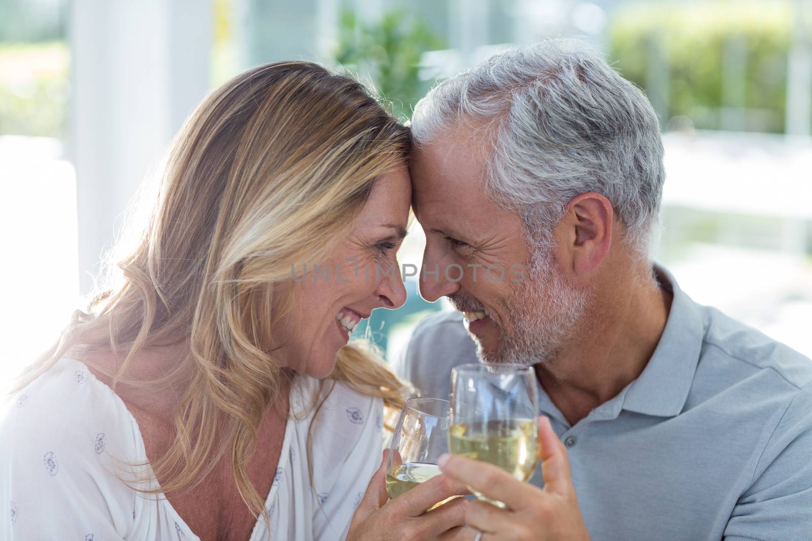 Close-up of romantic mature couple holding wineglass in restaurant