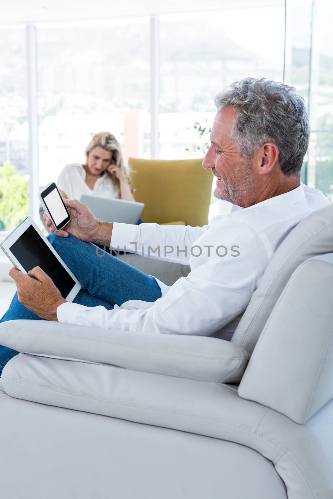 Smiling man using technology with woman in background
