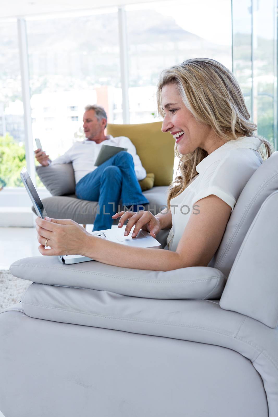 Happy woman with laptop and man using technology by Wavebreakmedia