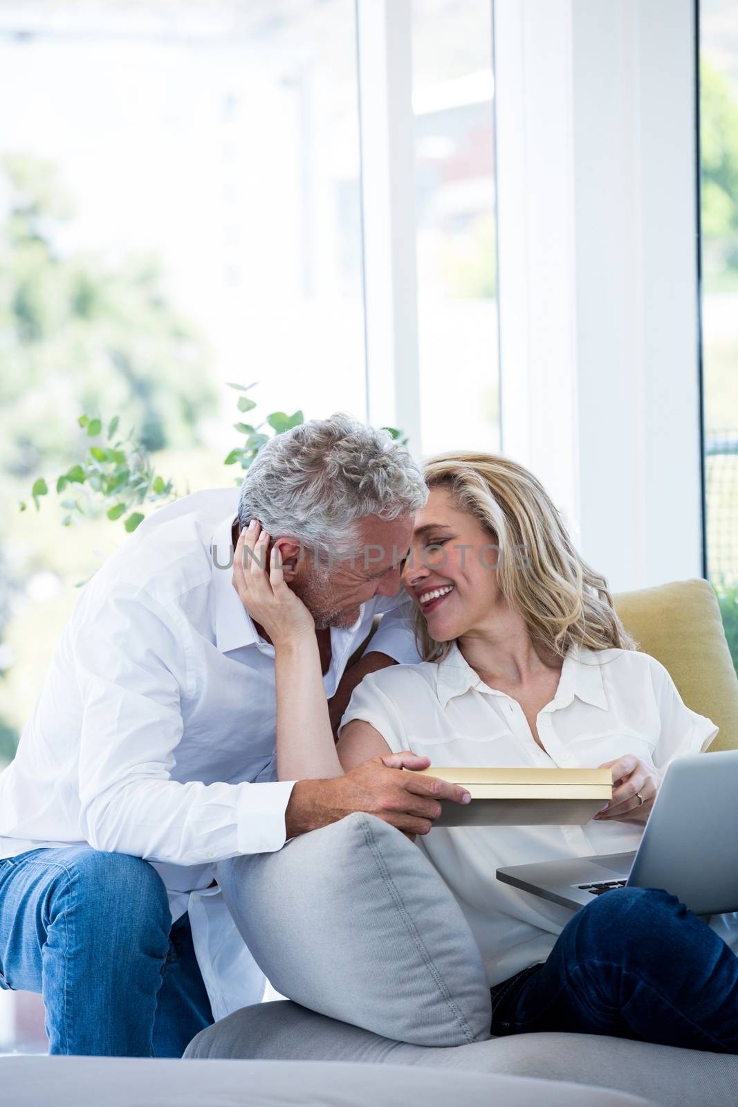 Romantic smiling mature couple with gift box at home