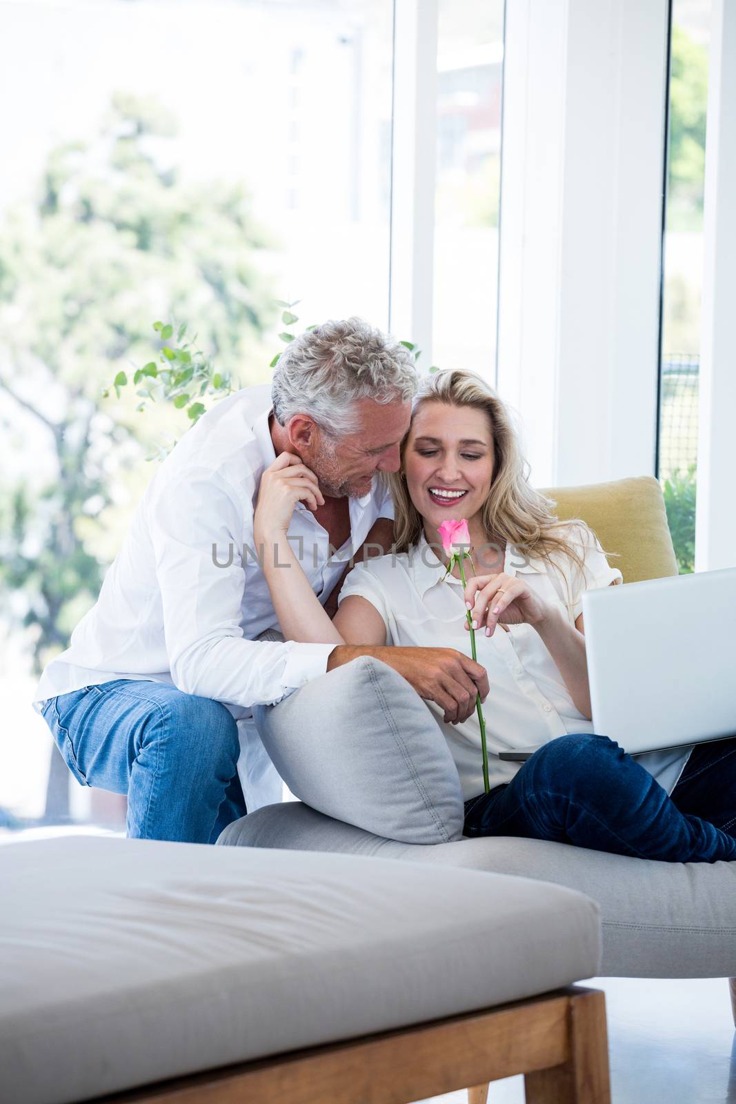 Romantic smiling mature couple with rose at home