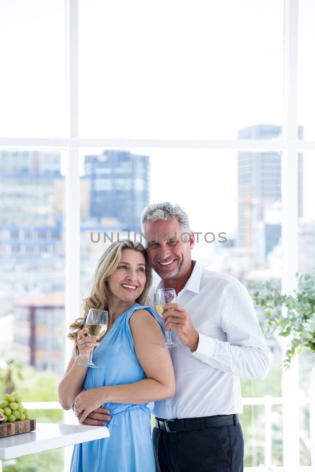 Romantic mature couple holding wine while standing at restaurant