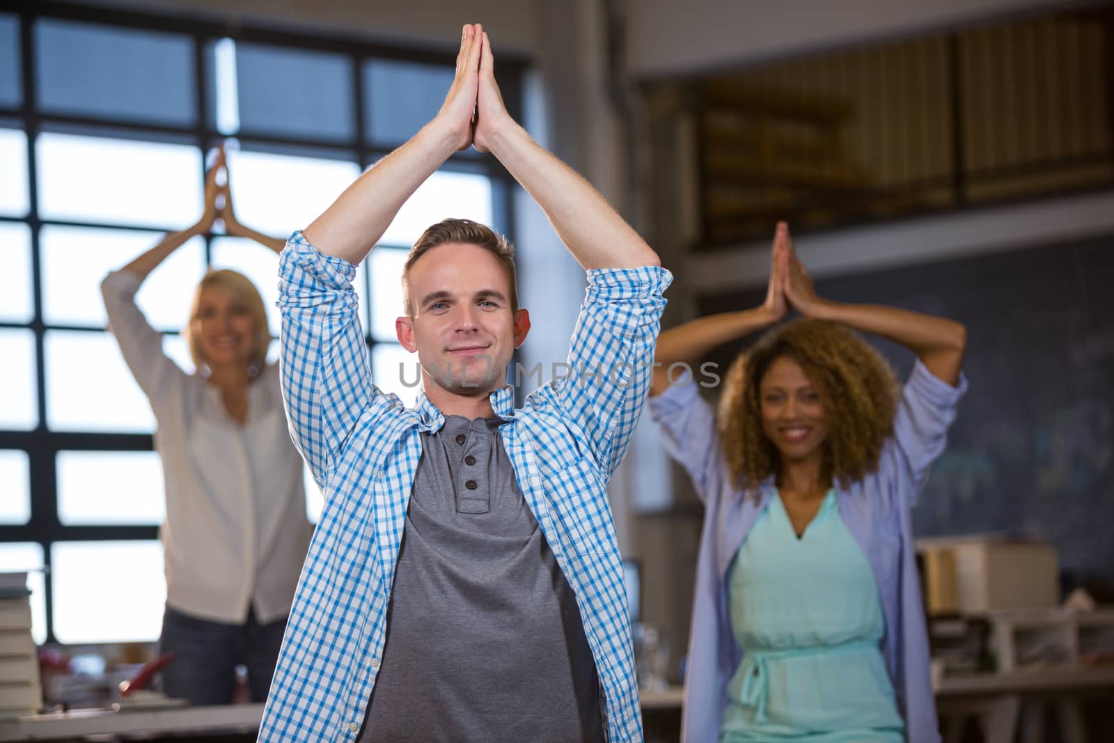 Business people smiling while practicing yoga in creative office