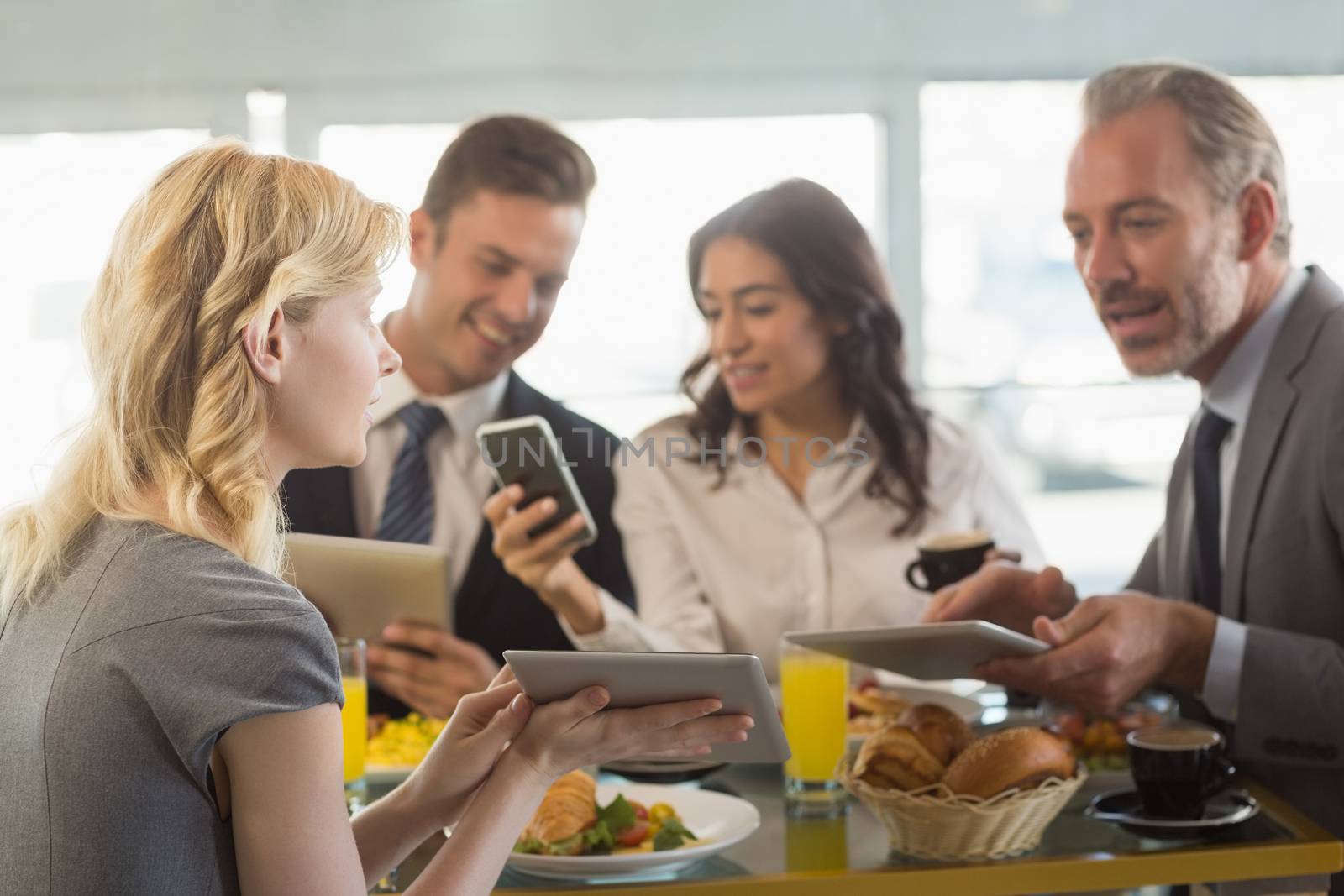 Business people using digital tablet and mobile phone while having meal in restaurant