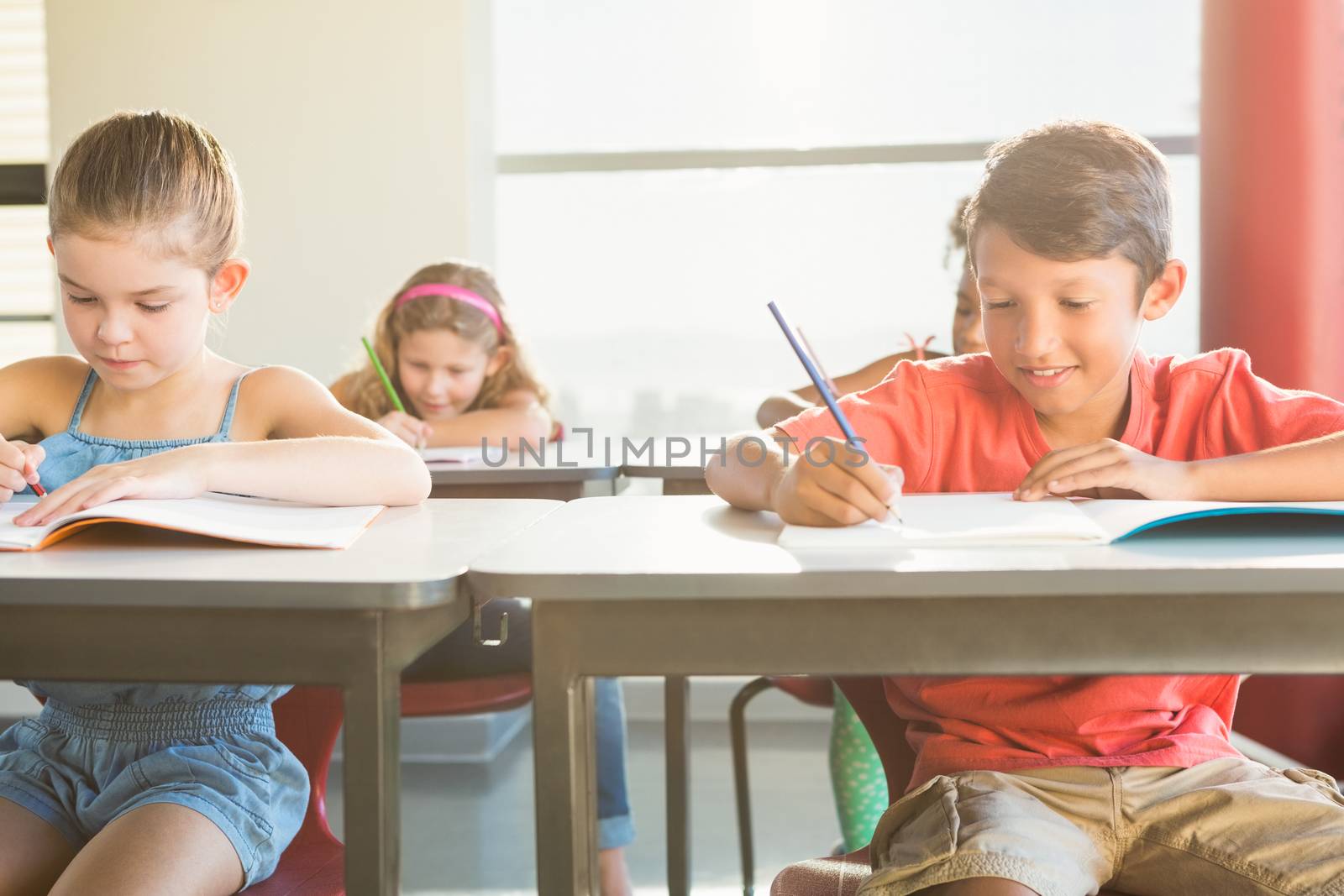 Schoolkids doning homework in classroom by Wavebreakmedia