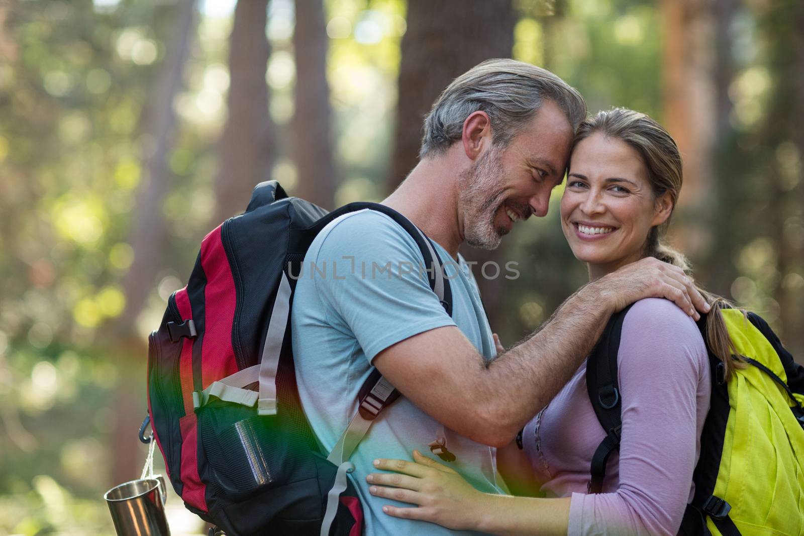 Romantic hiker couple embracing each other in forest