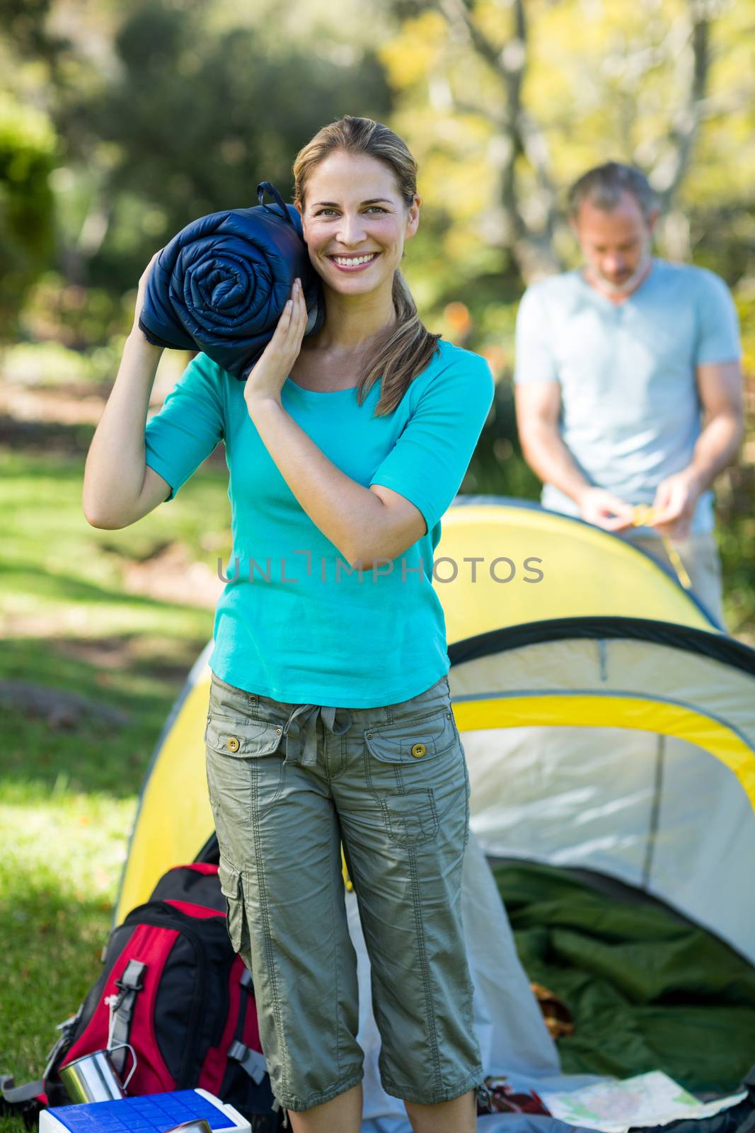 Beautiful female hiker holding travel bed in forest