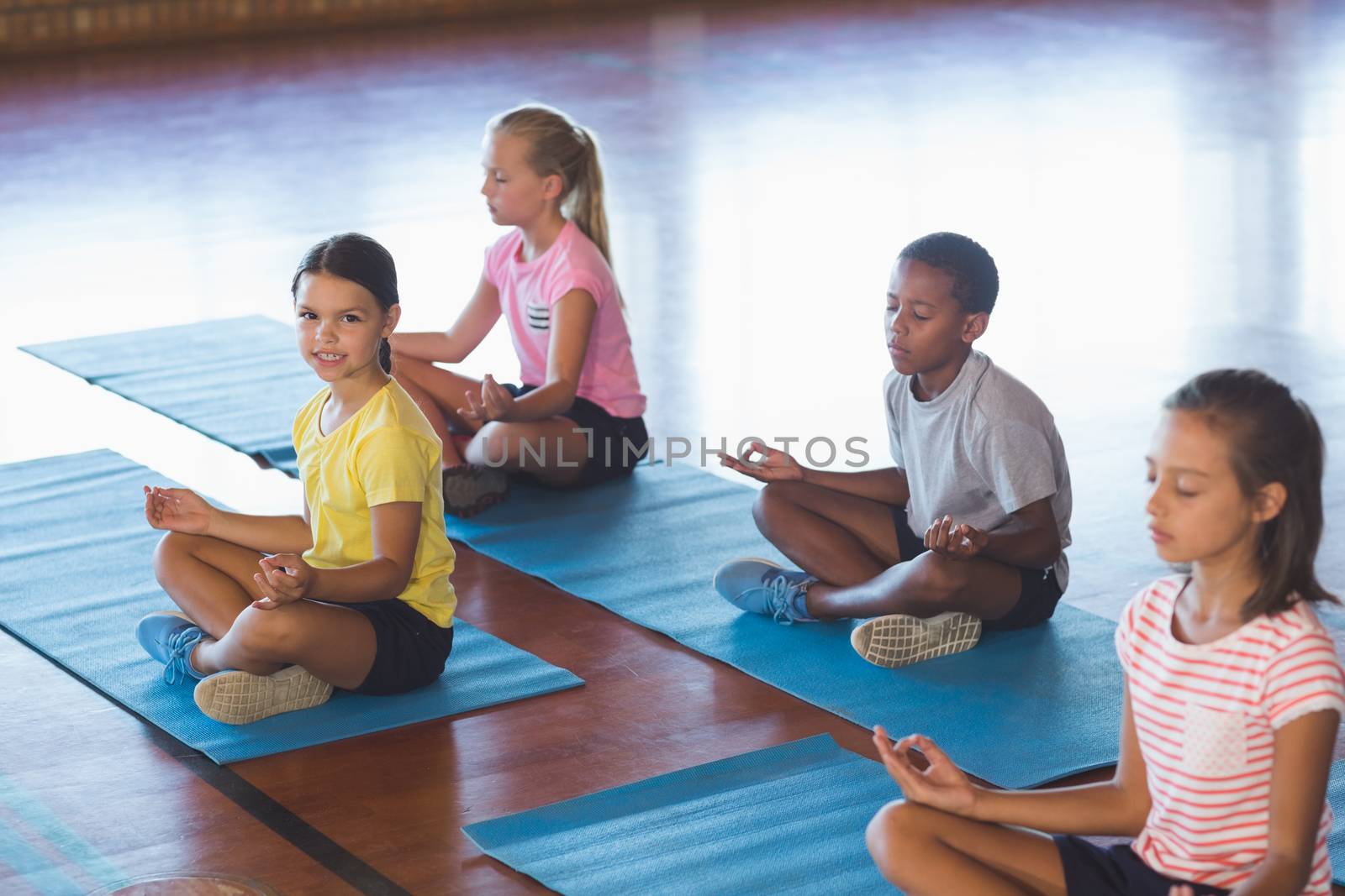 School kids meditating during yoga class by Wavebreakmedia