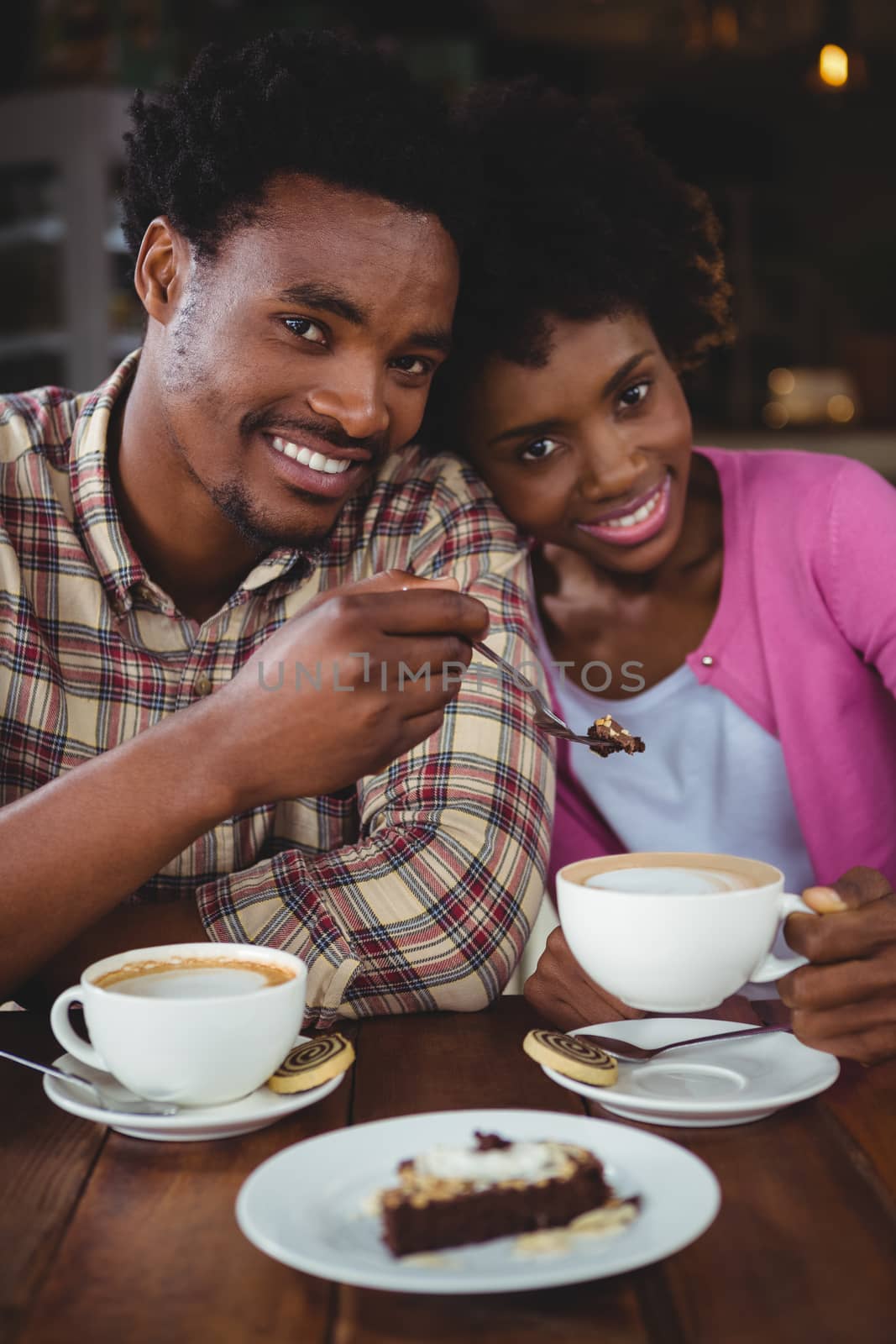 Portrait of happy young couple having breakfast in cafeteria