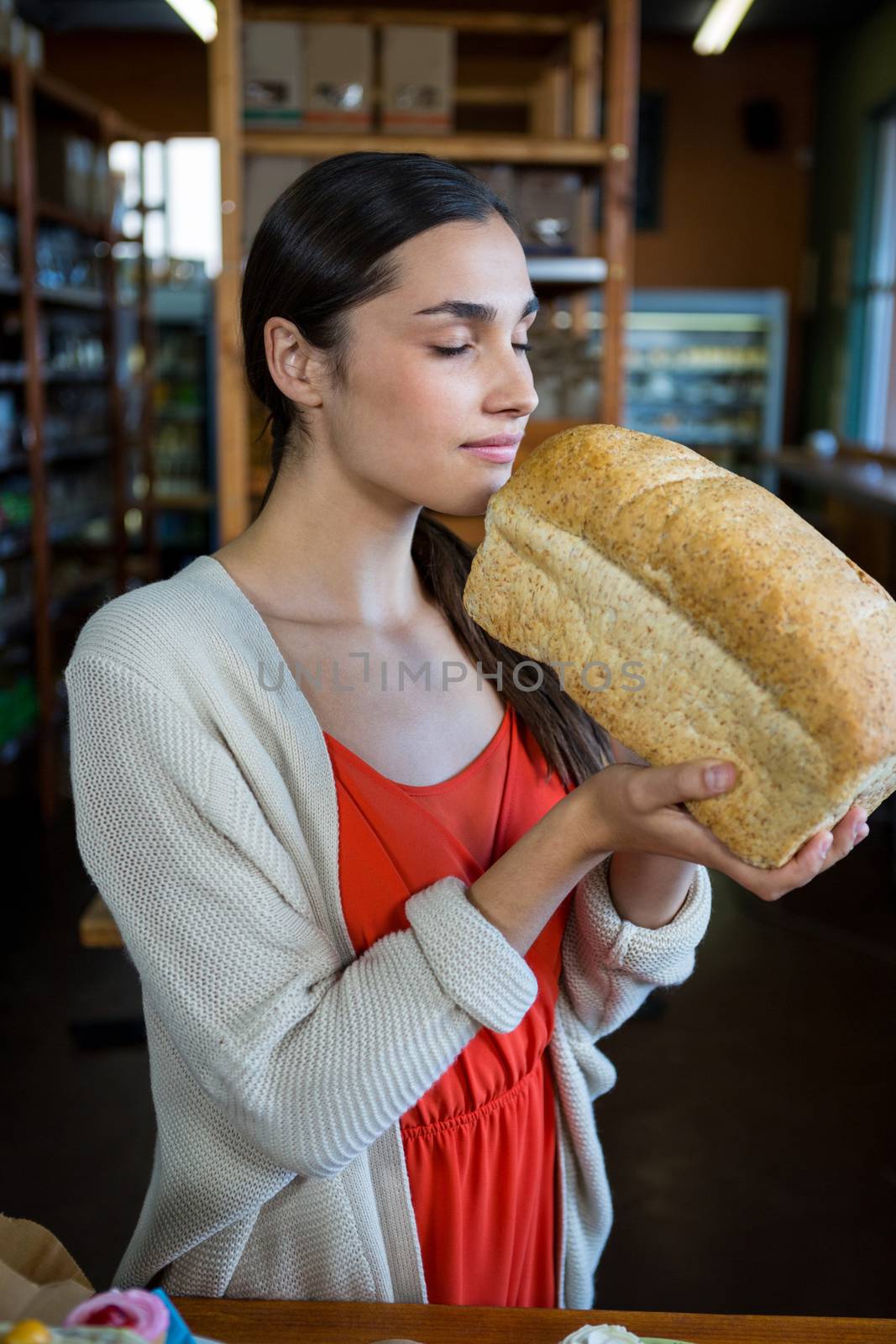 Woman smelling a loaf of bread in supermarket