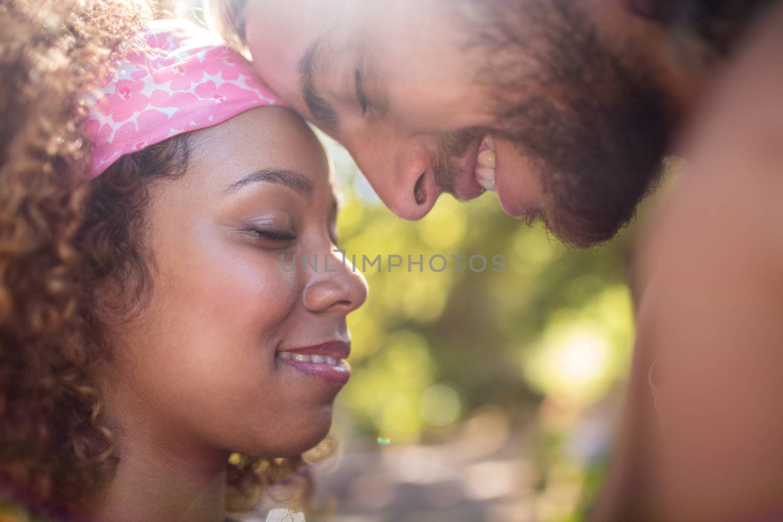 Romantic couple embracing each other with eyes closed in park on a sunny day