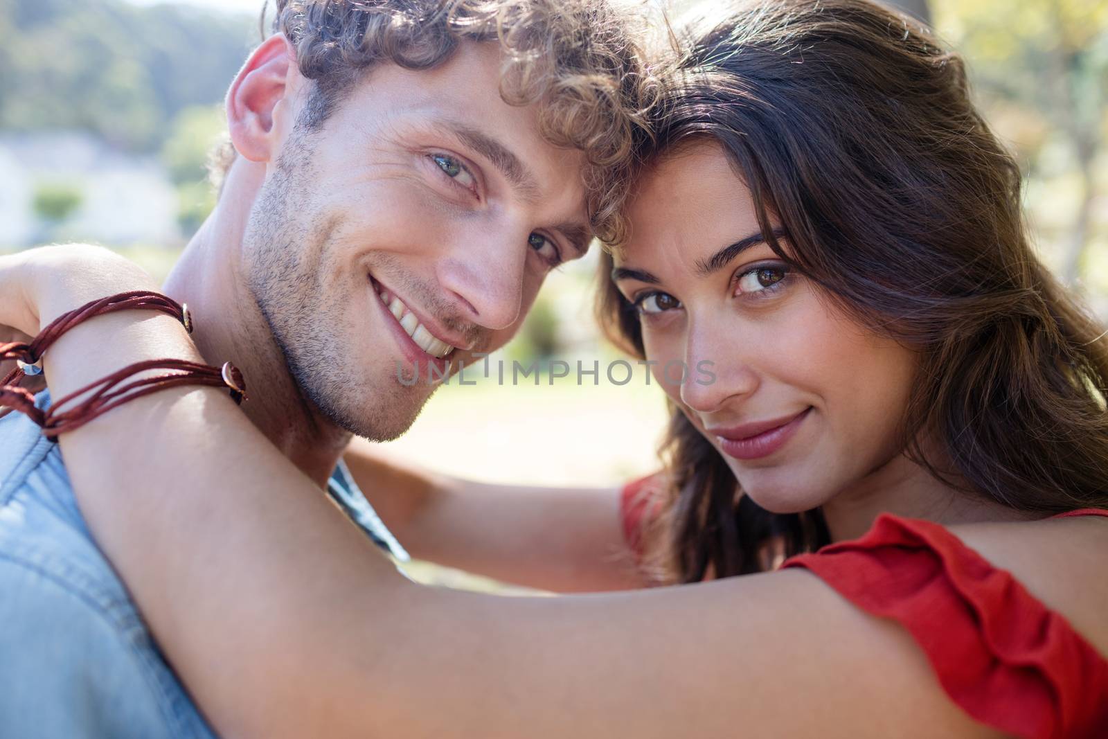 Portrait of romantic couple embracing each other in park on a sunny day