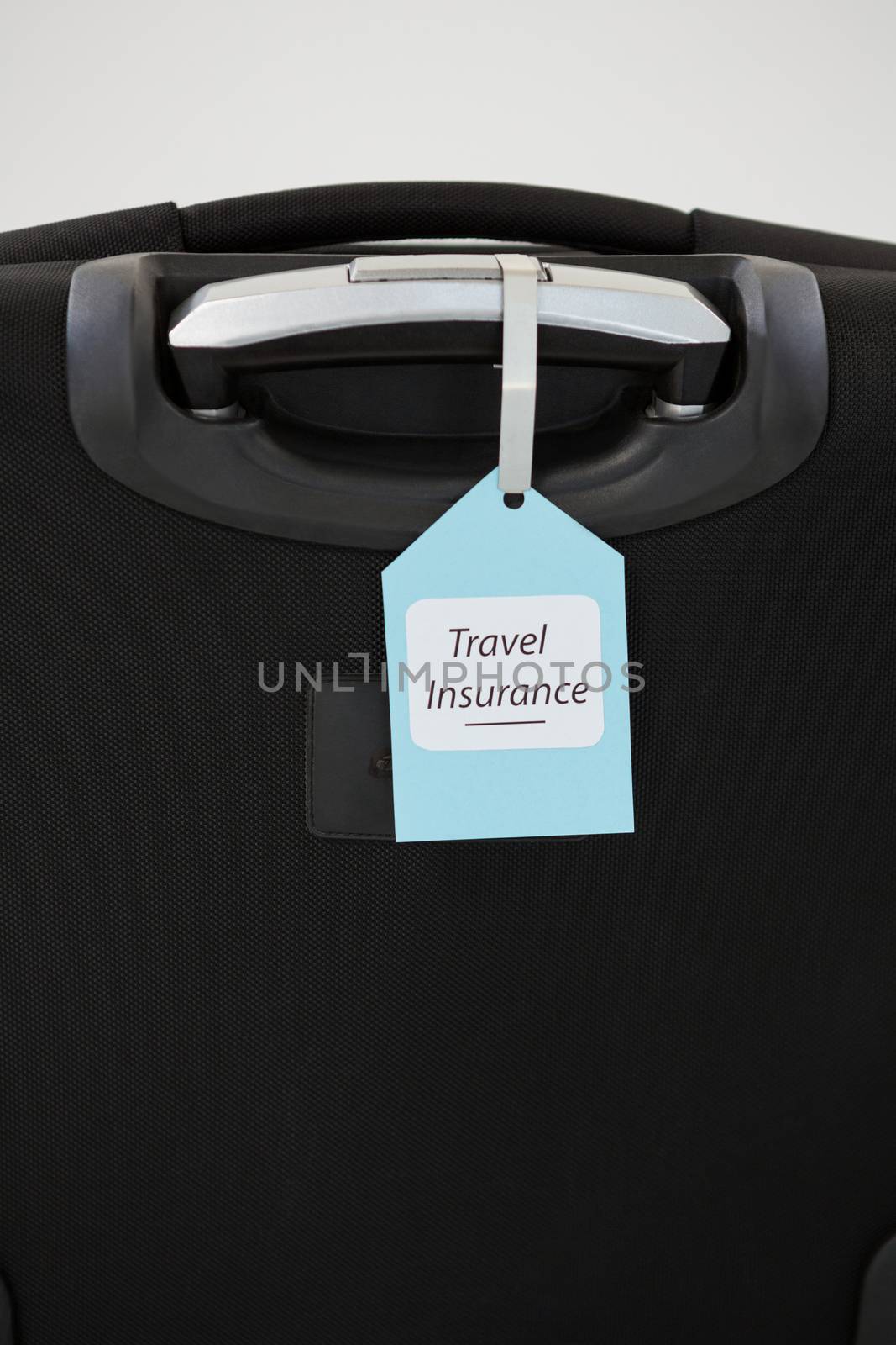 Close-up of travel insurance label tied to a suitcase