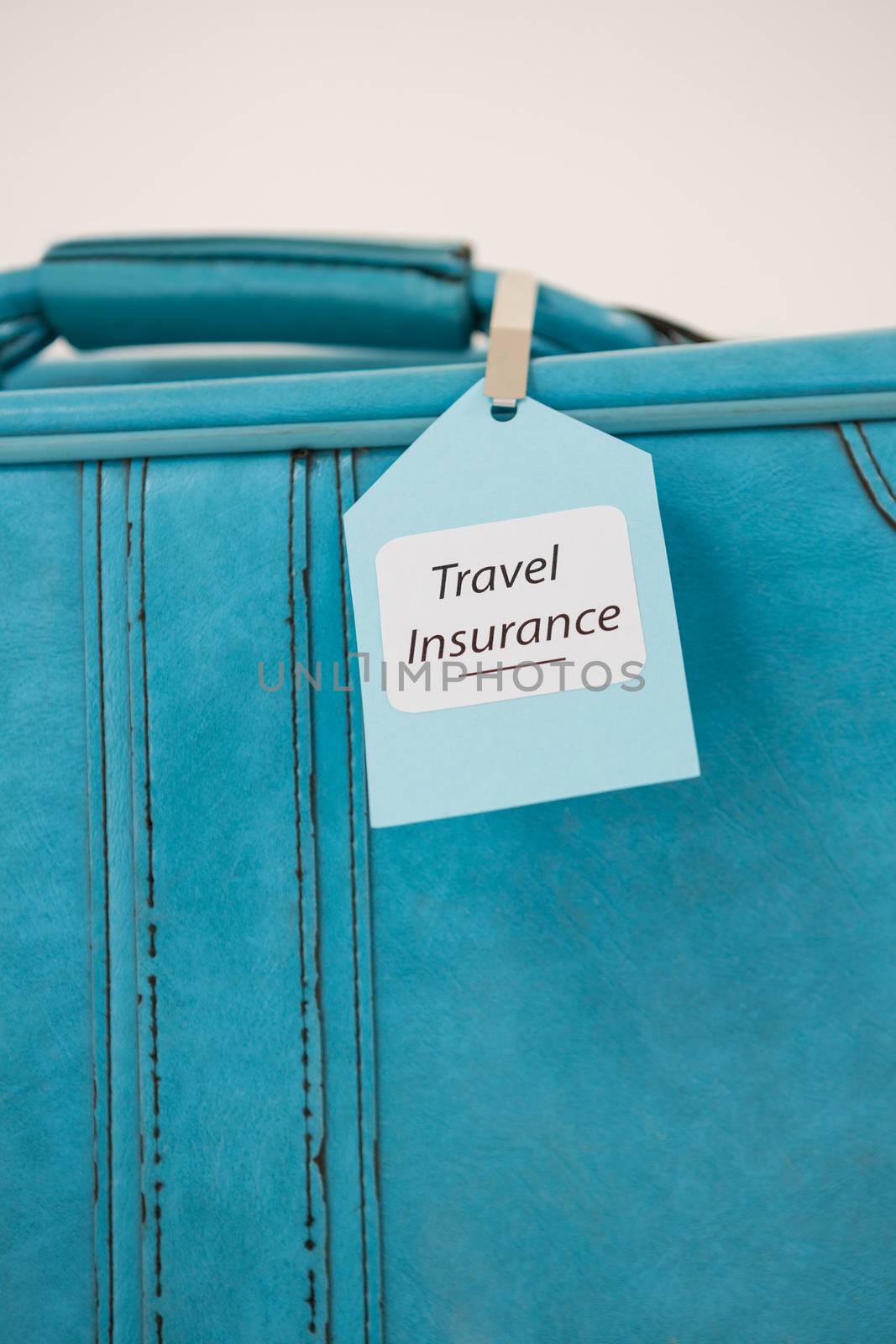 Close-up of travel insurance label tied to a suitcase