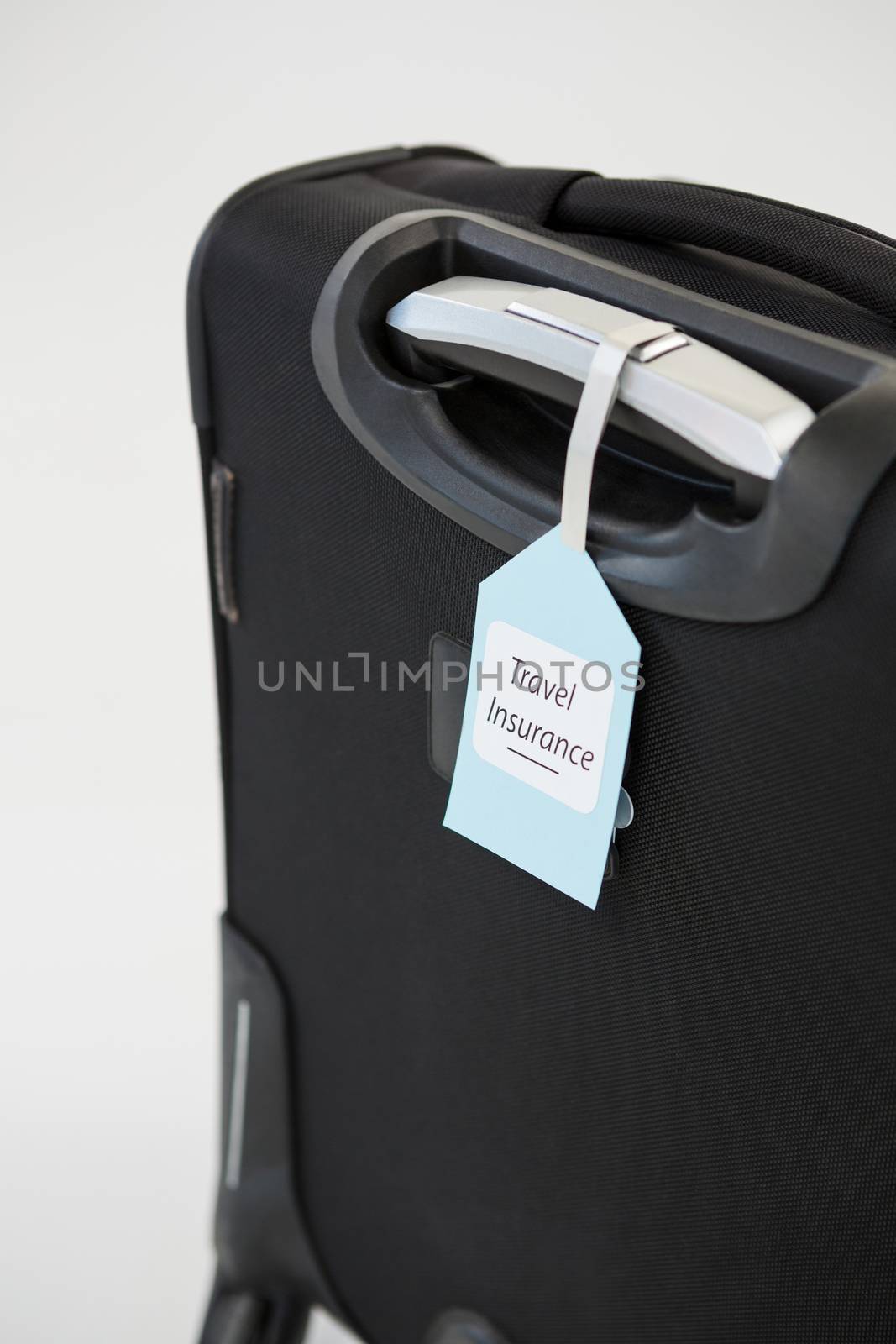 Travel insurance label tied to a suitcase by Wavebreakmedia