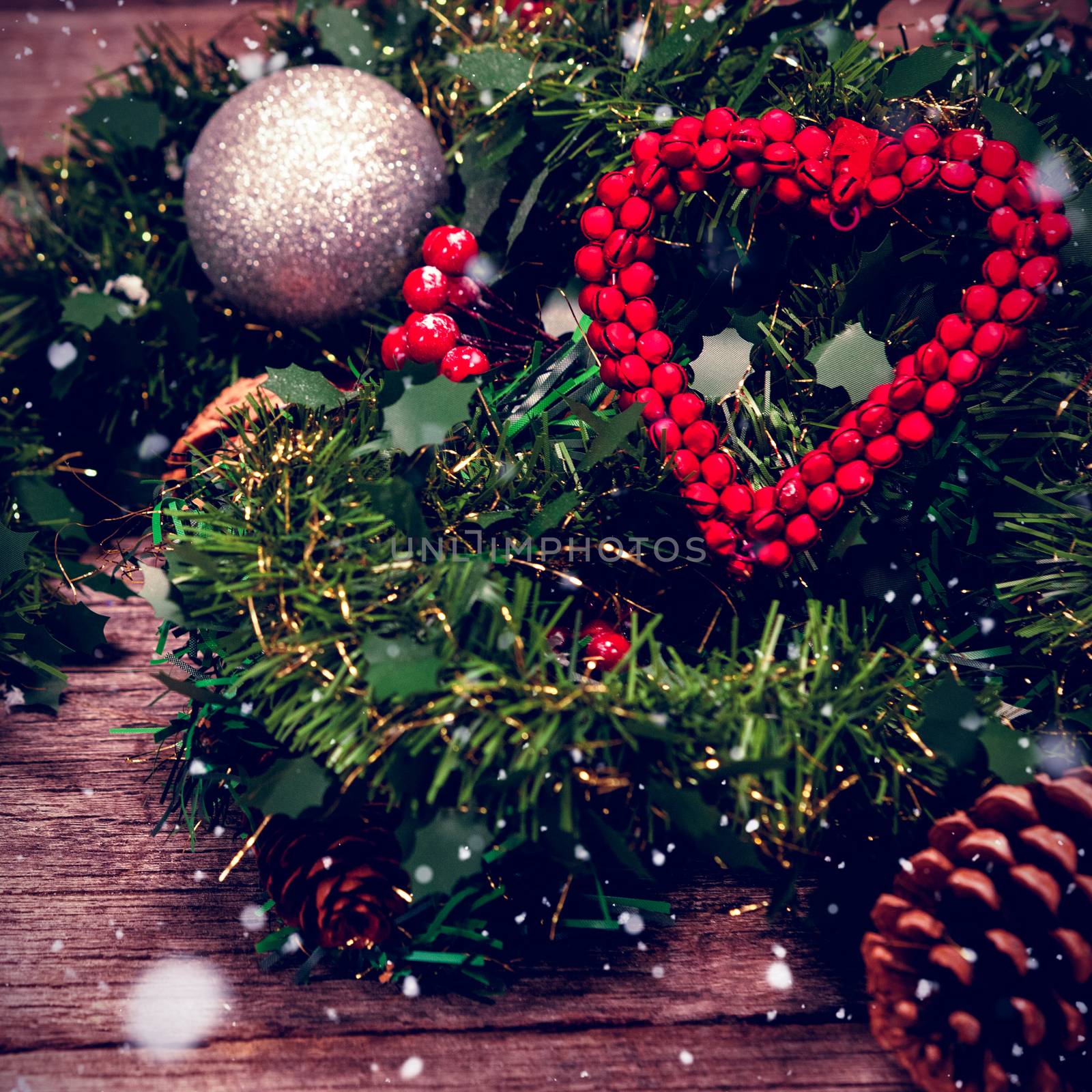 Snow falling against grapevine wreath with red ribbon and decoration