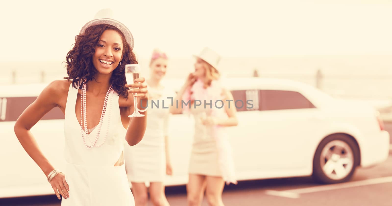 Portrait of women holding champagne while standing next to limousine at outdoors