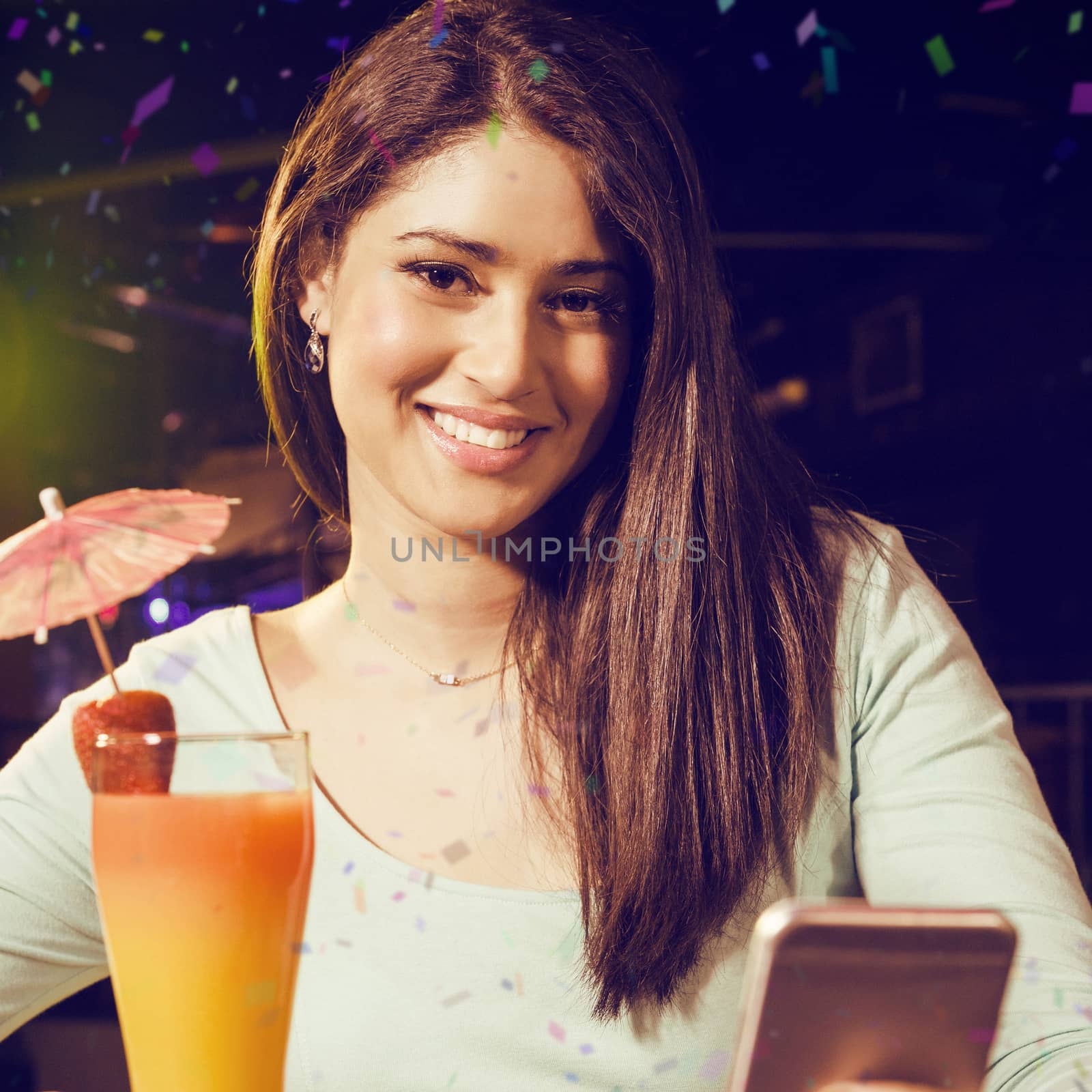 Portrait of woman typing text message while having cocktail against flying colours