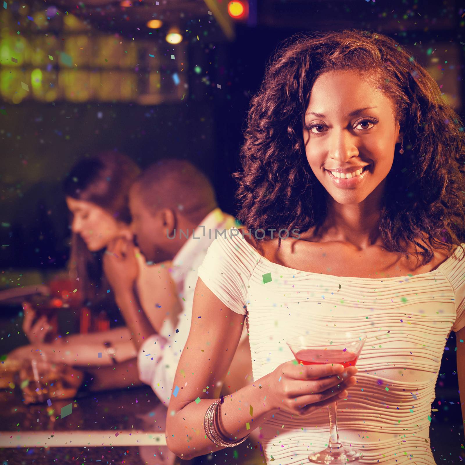 Portrait of young woman having cocktail at bar counter against flying colours