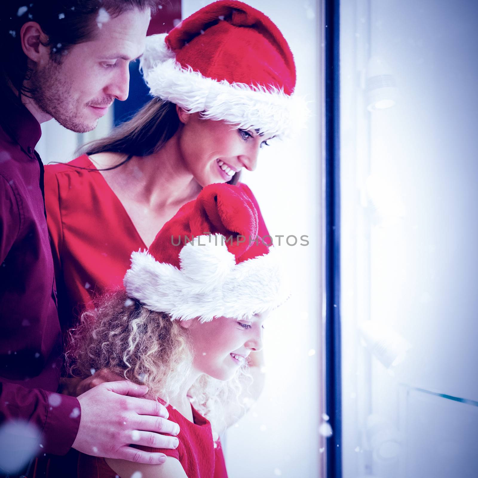 Side view of family in Christmas attire looking at display against snow falling