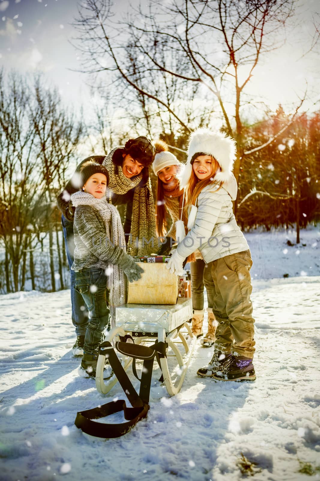 Portrait of happy family holding presents  against snow falling