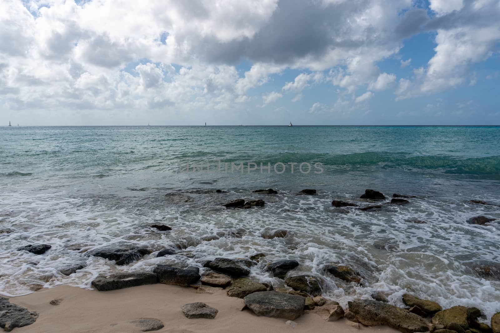 Panorama of the Caribbean Sea from the shore covered with large stones that break the waves

