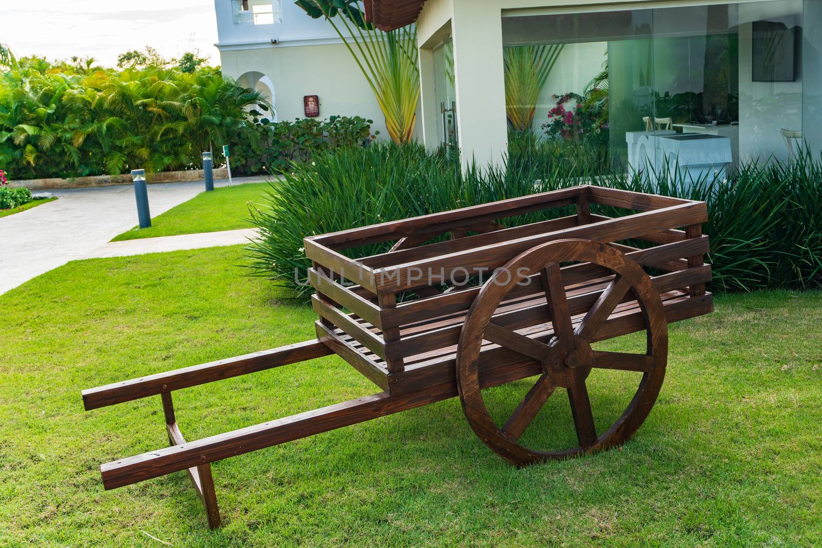 Wooden cart on the green grass lawn in front of the house by ben44