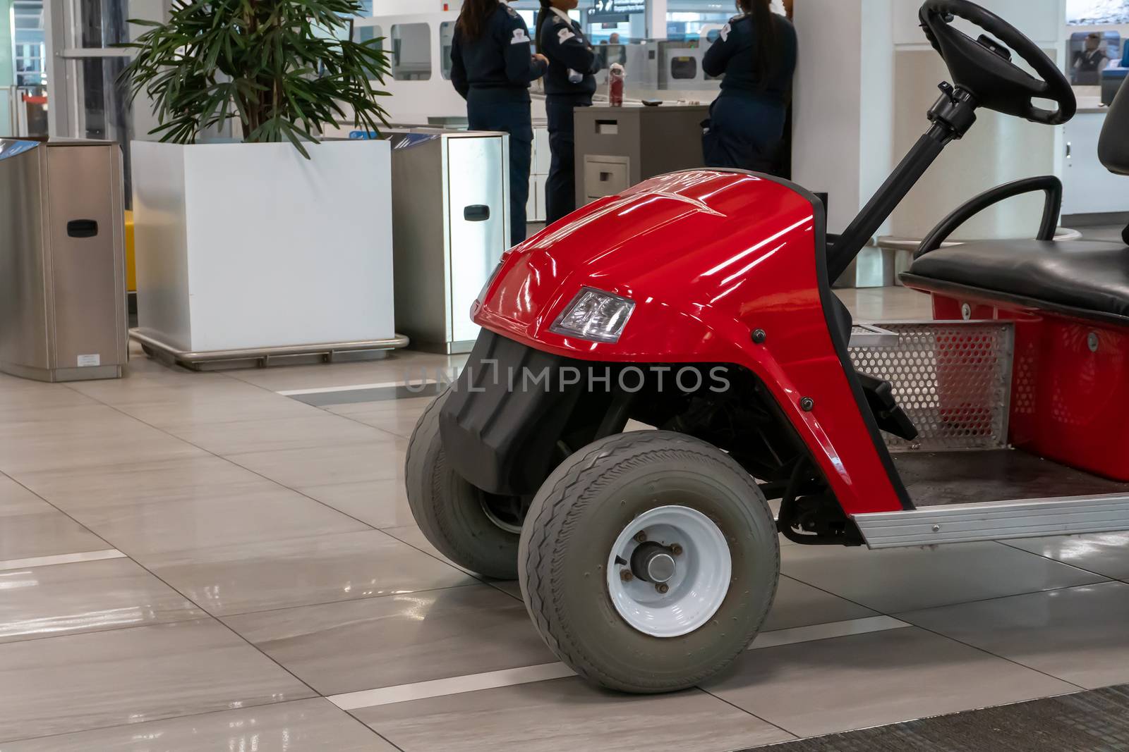 Fragment of a red car with an electric motor for transporting passengers and their luggage at the airport