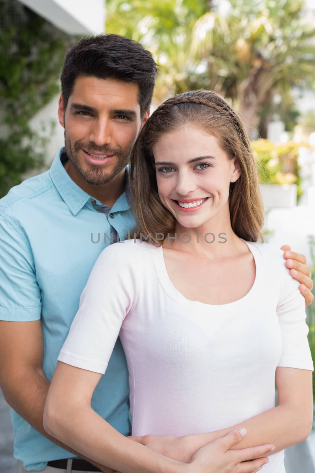 Portrait of a loving young man embracing woman from behind outdoors