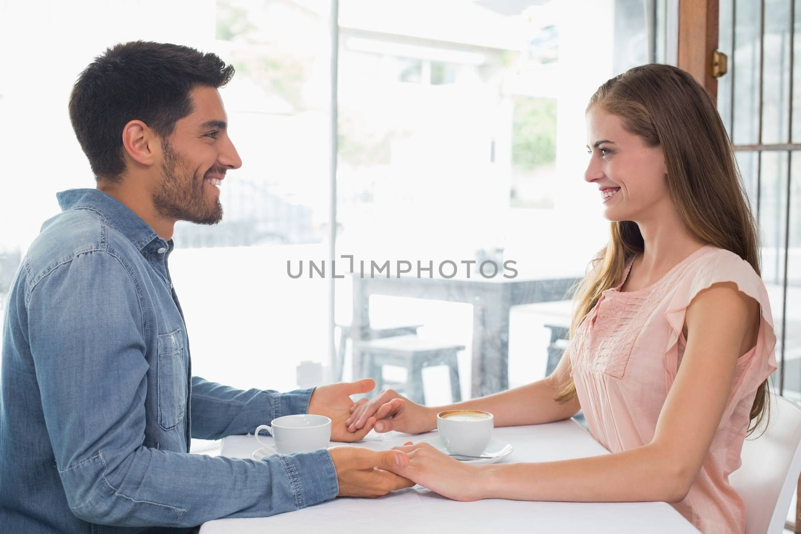 Romantic couple holding hands at coffee shop by Wavebreakmedia