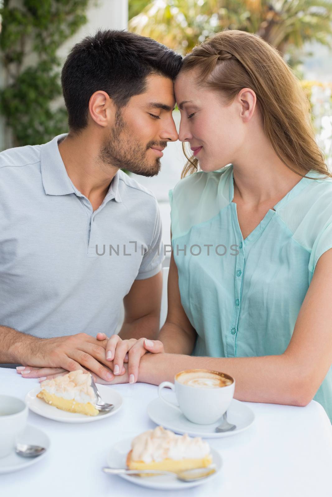 Romantic young couple sitting with eyes closed at the coffee shop