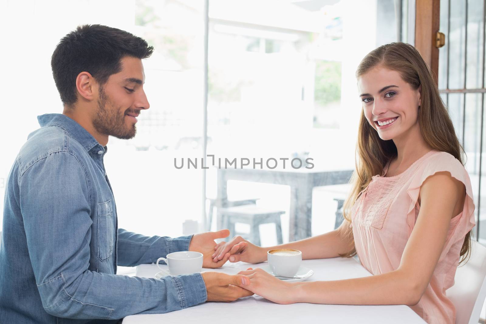 Romantic couple holding hands at coffee shop by Wavebreakmedia