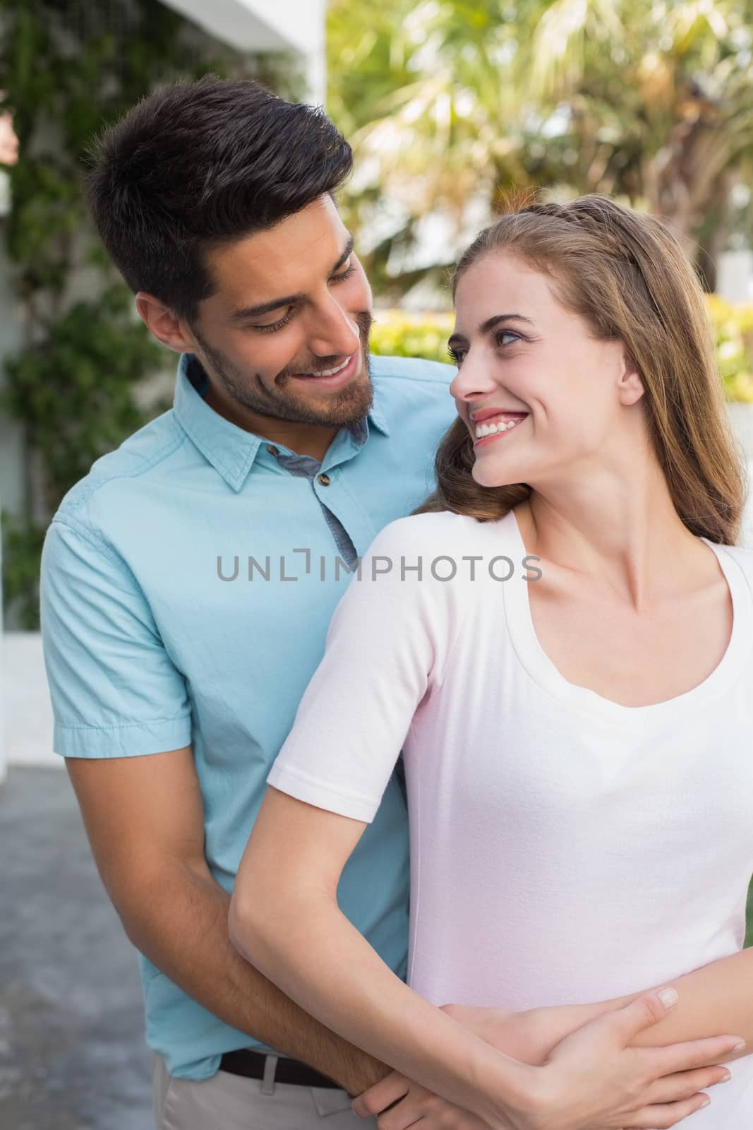 Portrait of a loving young man embracing woman from behind outdoors