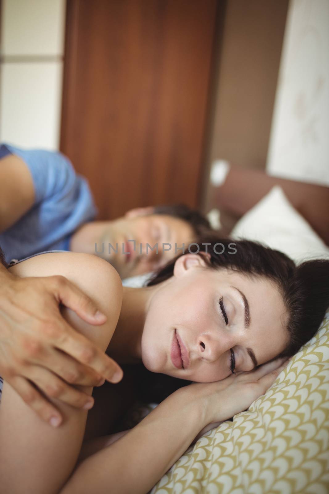 Romantic couple sleeping on bed by Wavebreakmedia