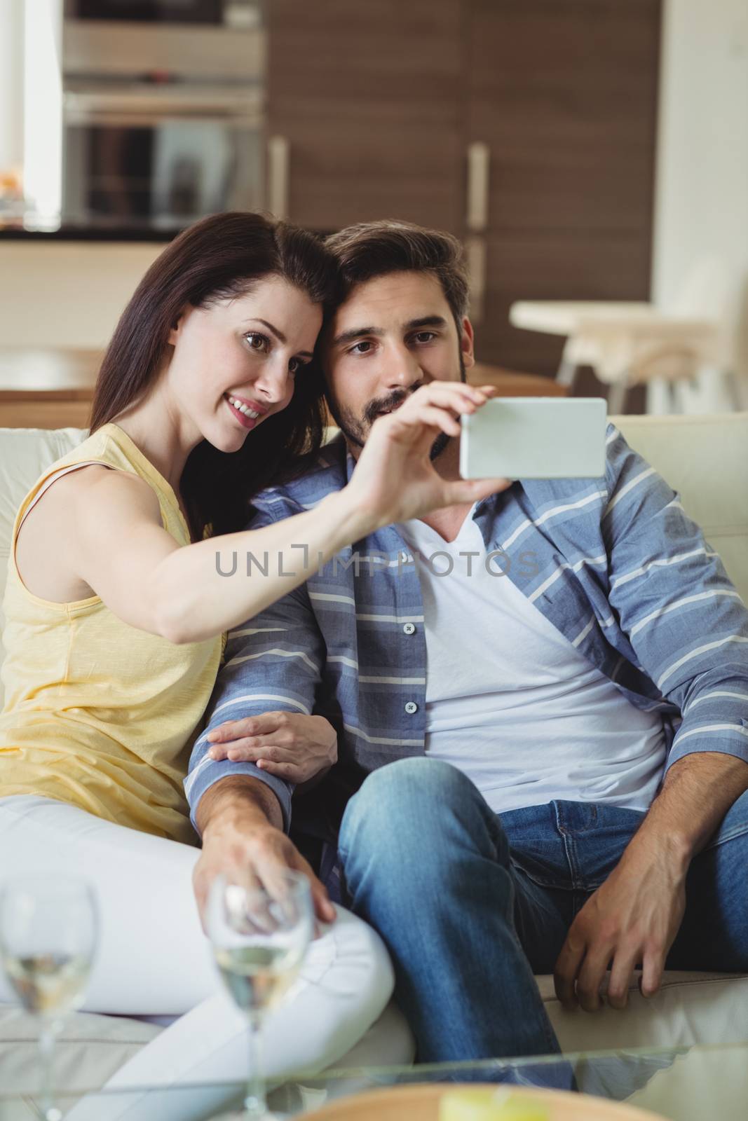 Romantic couple relaxing on sofa and taking a selfie in living room