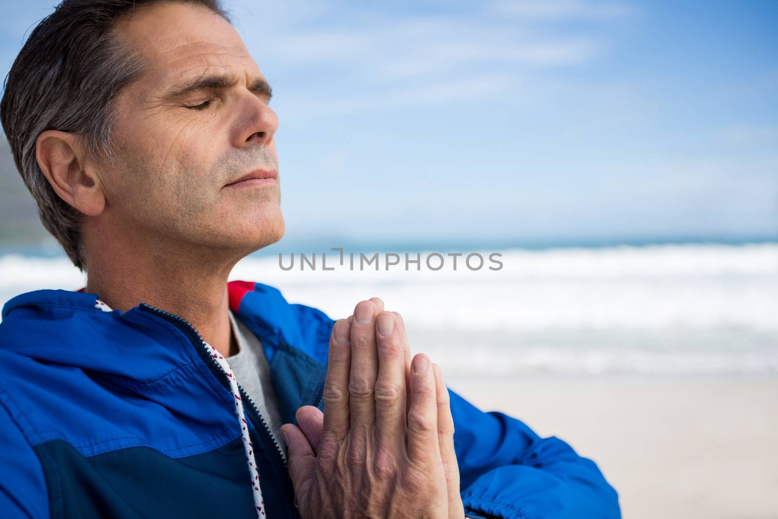 Mature man performing yoga on beach