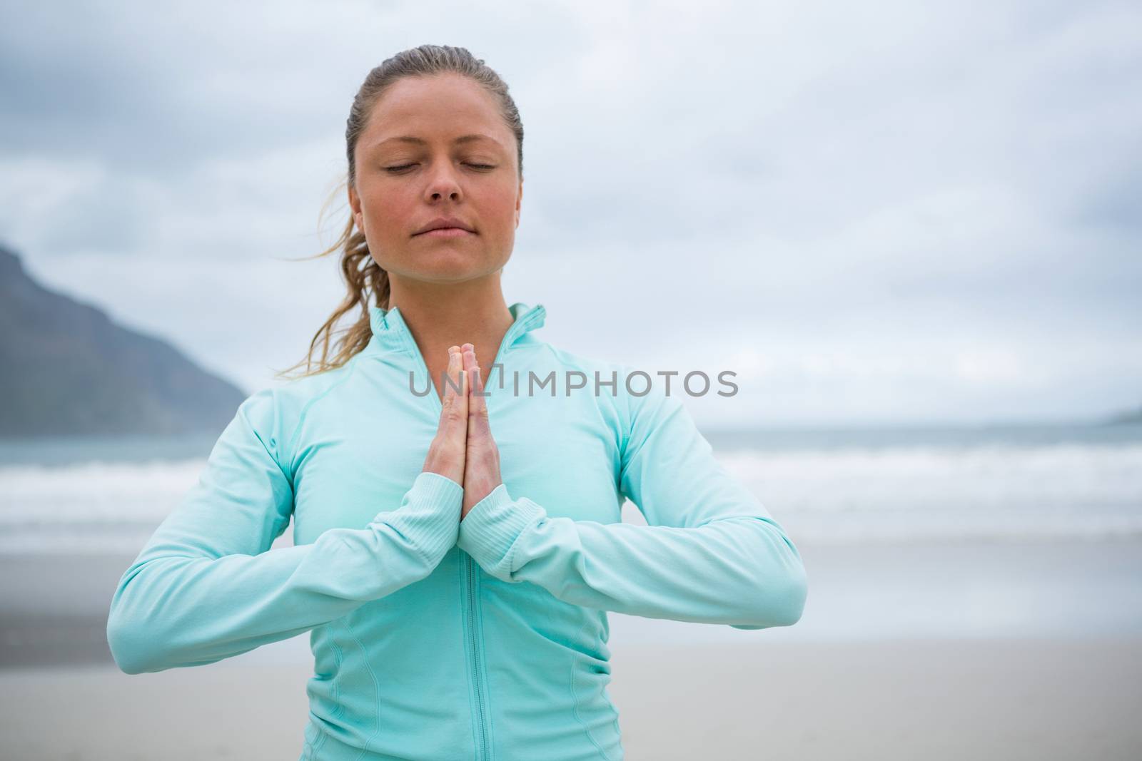 Woman performing yoga on beach during winter